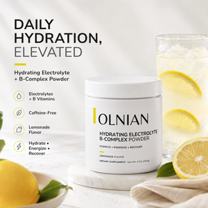 A white tub of OLNIAN Hydrating Electrolyte B-Complex Powder sits on a marble coaster, surrounded by lemons and a glass of lemonade. The background is a clean white with promotional text highlighting key benefits like caffeine-free and lemonade flavor.