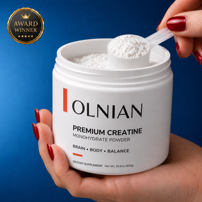 A white plastic tub of OLNIAN Premium Creatine Monohydrate Powder held by hands with red manicured nails, with a clear scoop filled with the white powder resting on the rim. The background is a solid dark blue, and a gold 'Award Winner' badge is in the top-left corner.
